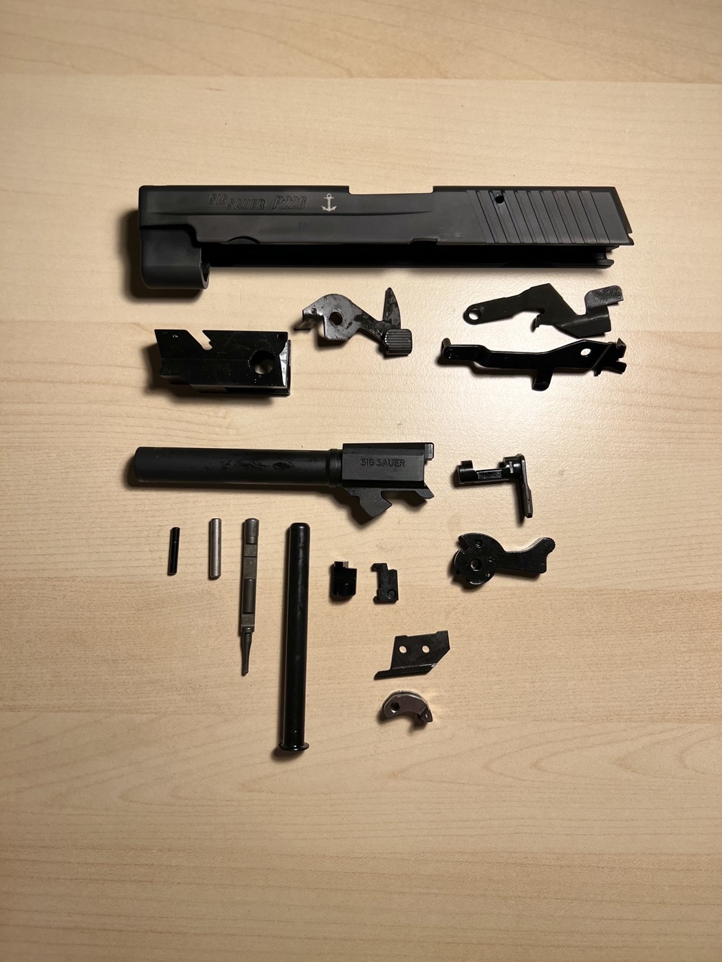 Sig Sauer P226 fully disassembled parts laid out after cryogenic treatment, micro-dimpling, and dry film lubrication