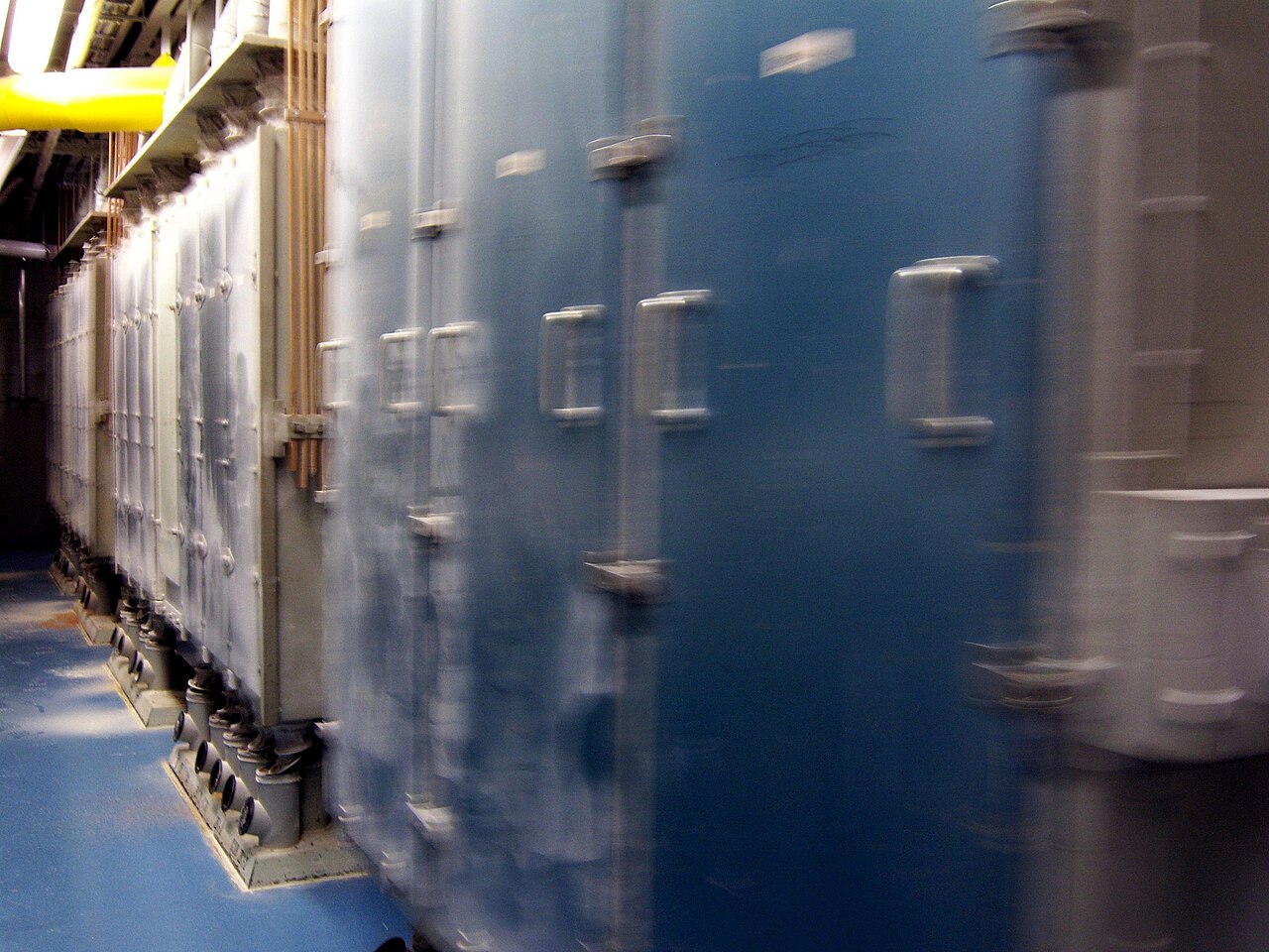A row of plansifters running in a flour mill, blurred by their own gyrating motion